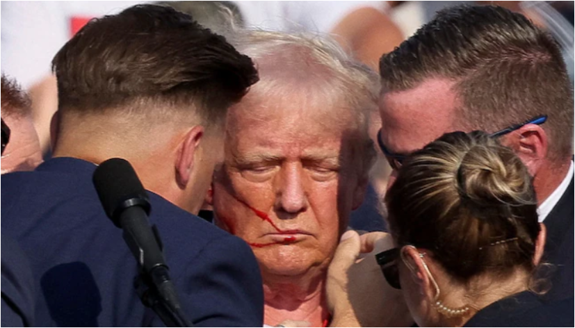 Donald Trump at a rally with his fist raised, blood streaked across his face, after narrowly avoiding an assassination attempt